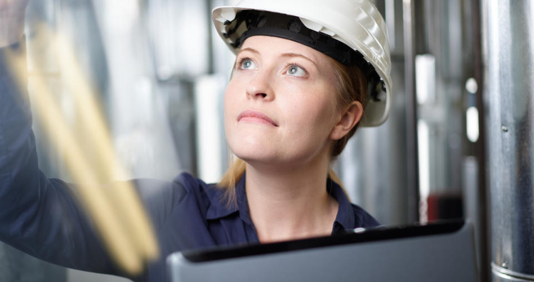 Mitarbeiterin mit Schutzhelm und Laptop